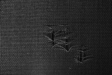 Torn window screen against black background, closeup Photo of Torn window screen against black background, closeup