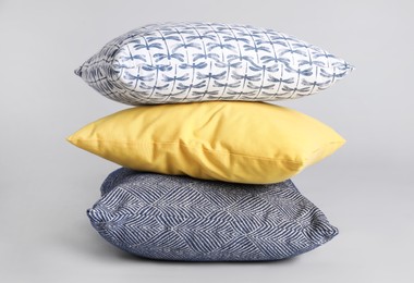 Stack of stylish soft pillows on grey background Photo of Stack of stylish soft pillows on grey background