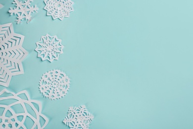 Flat lay composition with paper snowflakes on cyan background. Space for text Photo of Flat lay composition with paper snowflakes on cyan background. Space for text