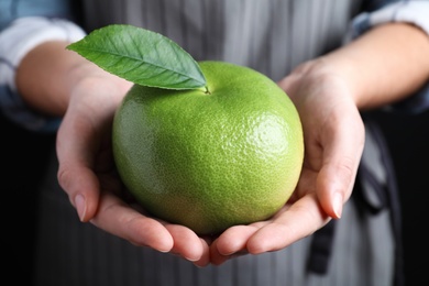 Photo of Woman holding fresh ripe sweetie fruit, closeup