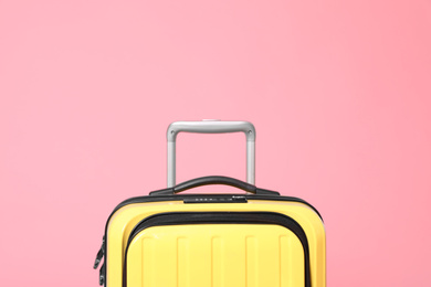 Photo of Stylish yellow suitcase packed for travel on pink background