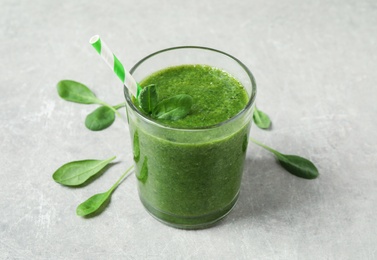 Green juice and fresh spinach leaves on light grey table Photo of Green juice and fresh spinach leaves on light grey table