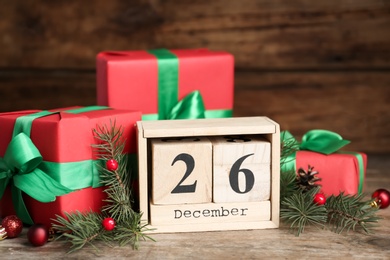 Block calendar with Boxing Day date near gifts on wooden table Photo of Block calendar with Boxing Day date near gifts on wooden table