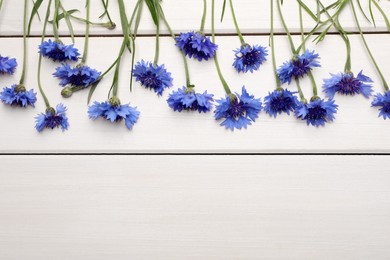 Beautiful blue cornflowers on white wooden background, flat lay. Space for text Photo of Beautiful blue cornflowers on white wooden background, flat lay. Space for text