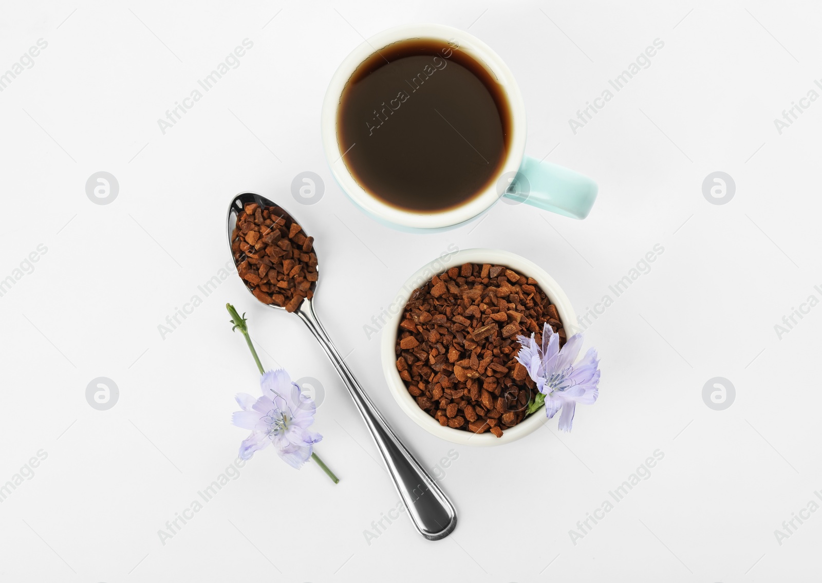 Photo of Cup of delicious chicory drink, granules and flowers on white background, top view