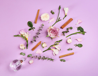 Photo of Beautiful flat lay composition with bottle of perfume, cinnamon and flowers on lilac background