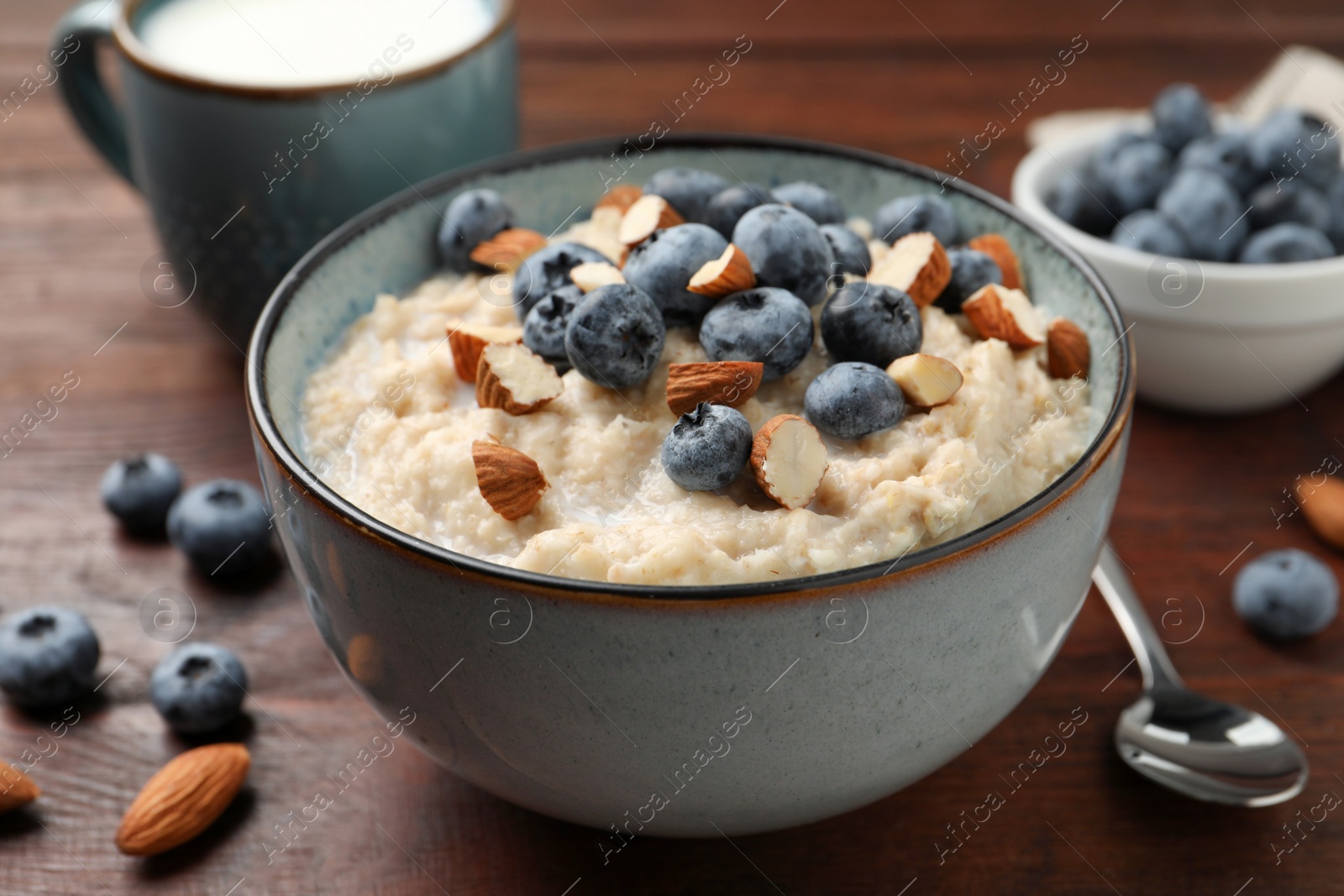 Tasty oatmeal porridge with blueberries and almond nuts on wooden table Photo of Tasty oatmeal porridge with blueberries and almond nuts on wooden table