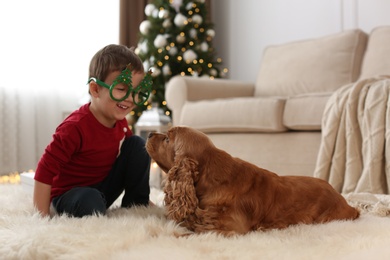 Cute little boy with English Cocker Spaniel in room decorated for Christmas Photo of Cute little boy with English Cocker Spaniel in room decorated for Christmas