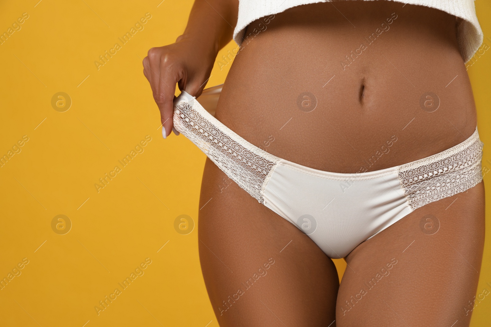 Woman in white sexy panties on yellow background, closeup. Space for text Photo of Woman in white sexy panties on yellow background, closeup. Space for text