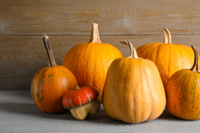 Many different ripe pumpkins on wooden table Photo of Many different ripe pumpkins on wooden table