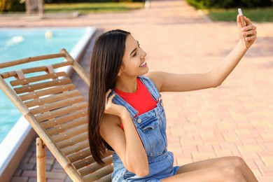 Young woman taking selfie in deck chair outdoors Image of Young woman taking selfie in deck chair outdoors