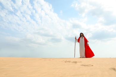 Jesus Christ walking with stick in desert. Space for text Photo of Jesus Christ walking with stick in desert. Space for text
