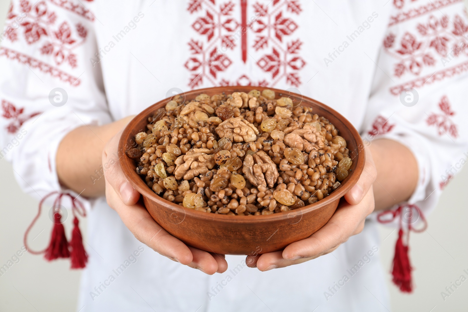 Woman in slavic shirt holding bowl with traditional kutia, closeup Photo of Woman in slavic shirt holding bowl with traditional kutia, closeup