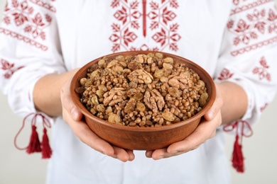 Woman in slavic shirt holding bowl with traditional kutia, closeup Photo of Woman in slavic shirt holding bowl with traditional kutia, closeup