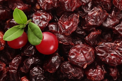 Tasty fresh and dried cranberries with leaves as background, closeup Photo of Tasty fresh and dried cranberries with leaves as background, closeup