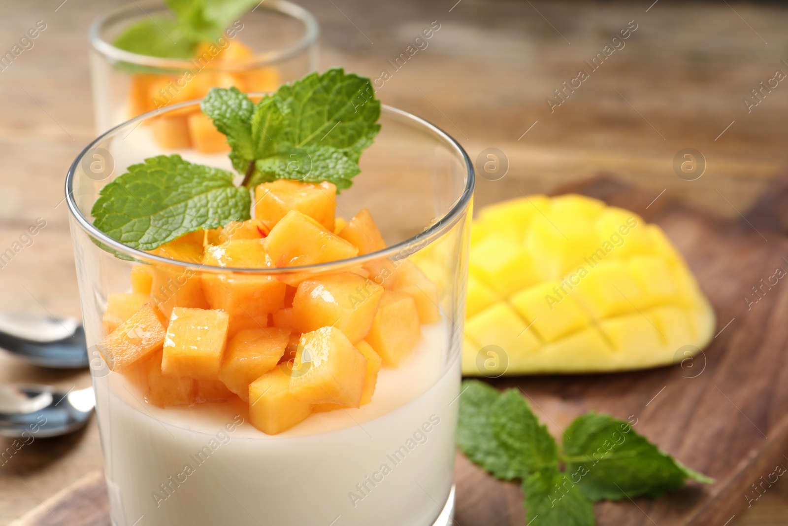 Delicious panna cotta with mango in glass dish on table, closeup Photo of Delicious panna cotta with mango in glass dish on table, closeup