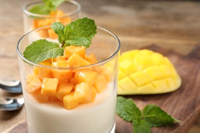 Delicious panna cotta with mango in glass dish on table, closeup Photo of Delicious panna cotta with mango in glass dish on table, closeup