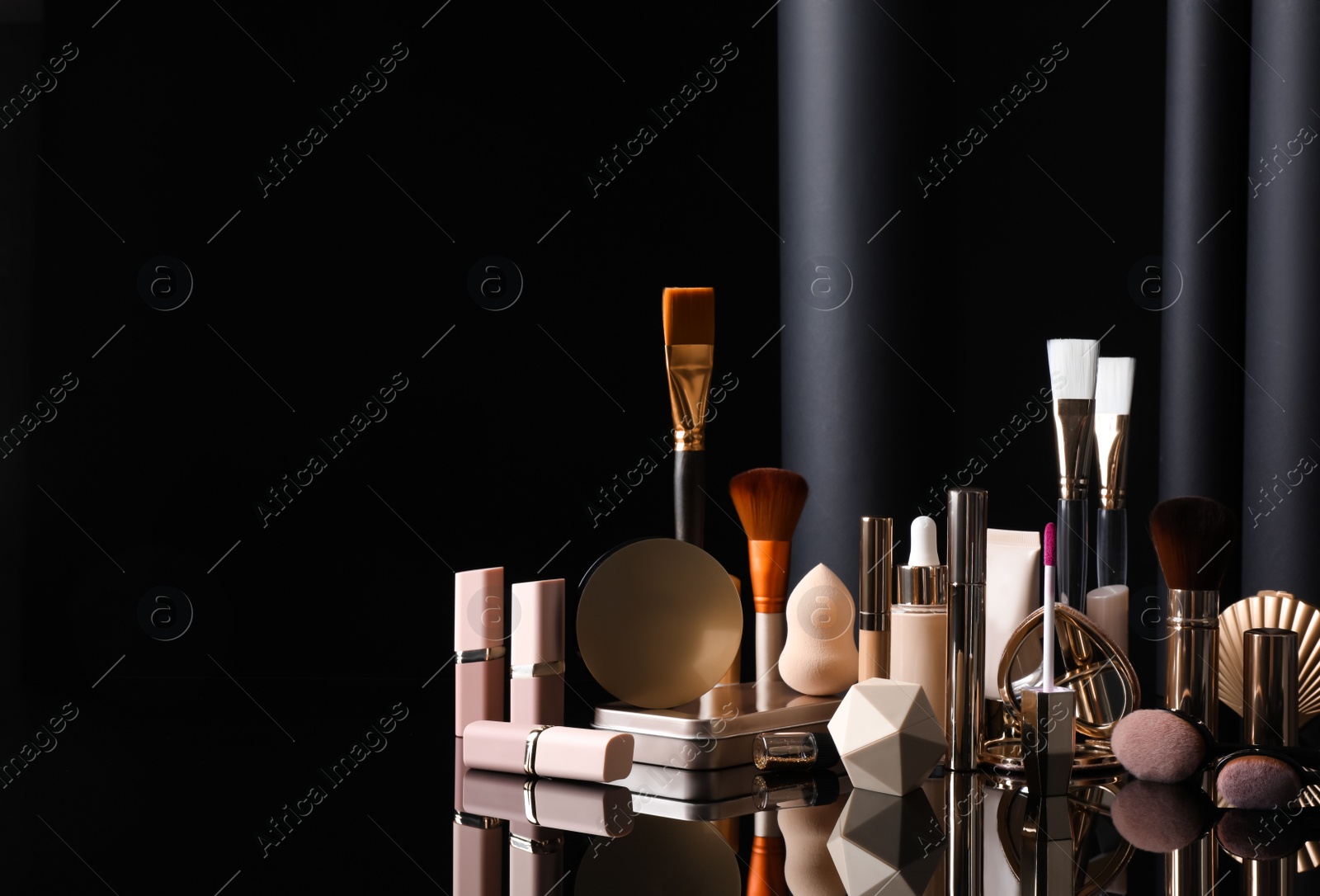 Composition with makeup products on table against black background Photo of Composition with makeup products on table against black background