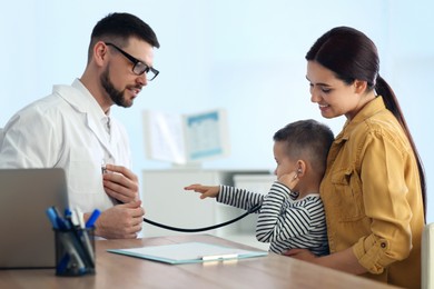 Mother and son visiting pediatrician in hospital. Doctor examining little boy Photo of Mother and son visiting pediatrician in hospital. Doctor examining little boy