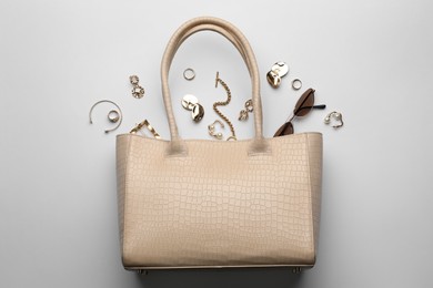 Stylish woman's bag, sunglasses and bijouterie on light background, flat lay Photo of Stylish woman's bag, sunglasses and bijouterie on light background, flat lay
