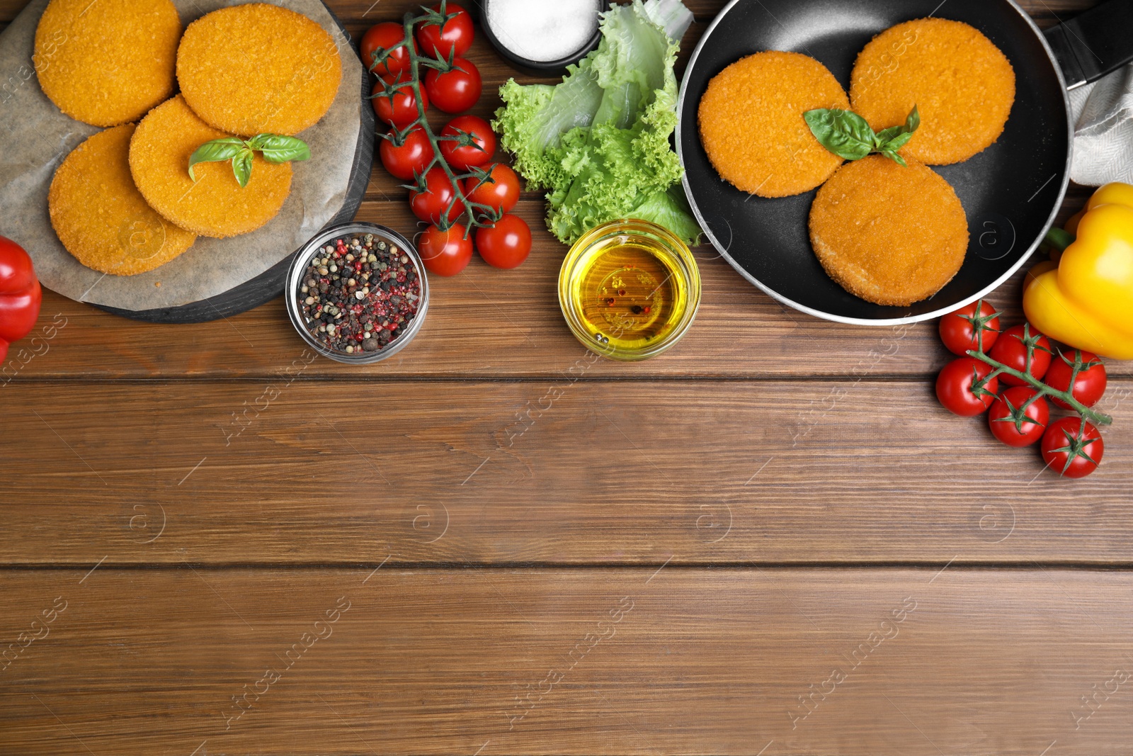 Delicious fried breaded cutlets, spices and vegetables on wooden table, flat lay. Space for text Photo of Delicious fried breaded cutlets, spices and vegetables on wooden table, flat lay. Space for text