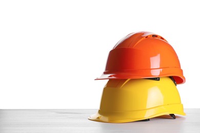 Different hard hats on wooden table against white background. Space for text Photo of Different hard hats on wooden table against white background. Space for text