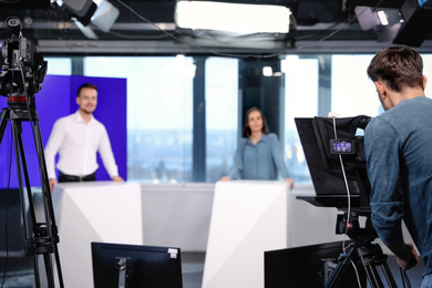 Photo of Presenters and video camera operator working in studio. News broadcasting