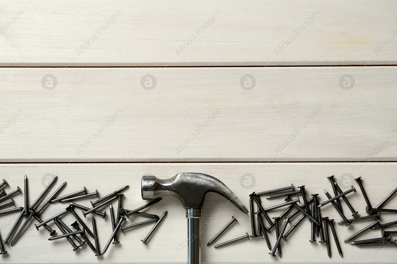 Hammer and metal nails on white wooden table, flat lay. Space for text Photo of Hammer and metal nails on white wooden table, flat lay. Space for text