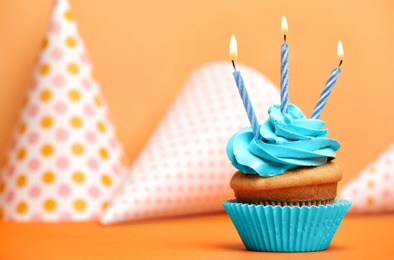 Birthday cupcake with candles on color background Photo of Birthday cupcake with candles on color background