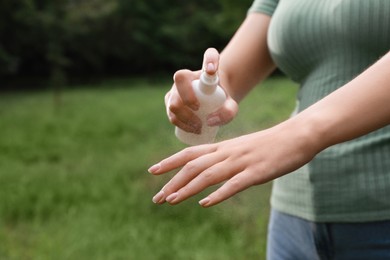 Woman applying insect repellent onto hand in park, closeup. Tick bites prevention Photo of Woman applying insect repellent onto hand in park, closeup. Tick bites prevention