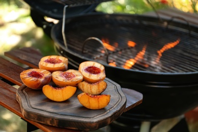 Delicious grilled peaches on wooden table outdoors Photo of Delicious grilled peaches on wooden table outdoors