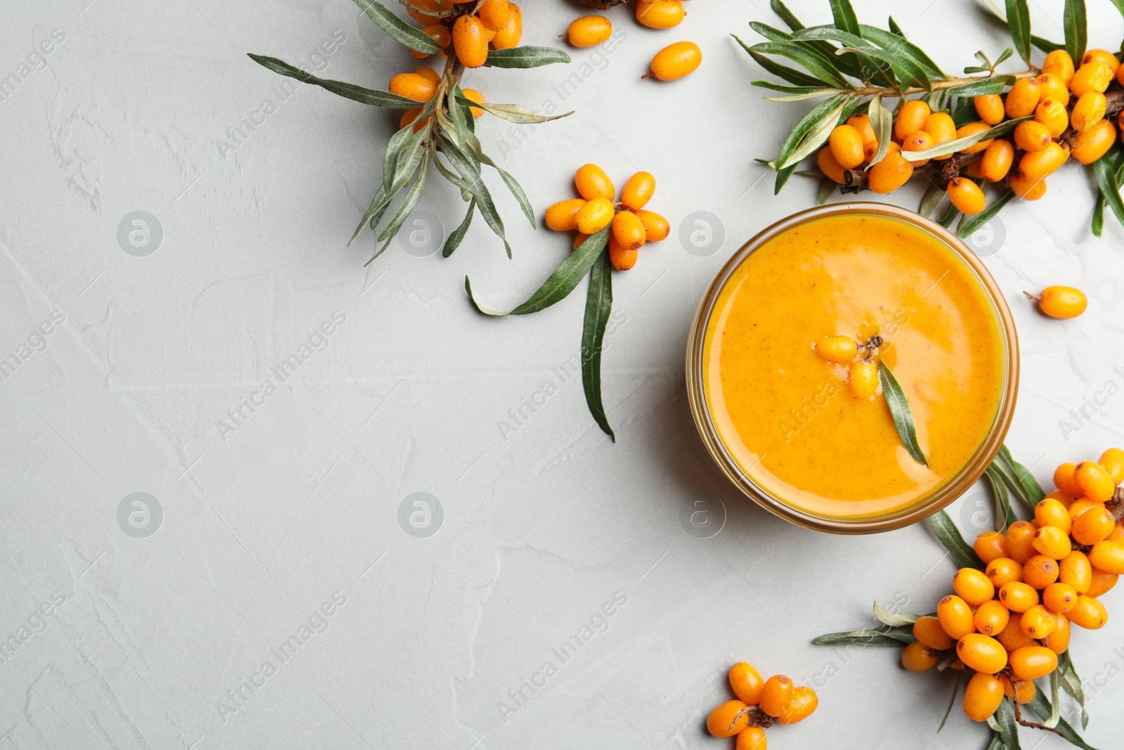 Delicious sea buckthorn jam and fresh berries on light grey table, flat lay. Space for text Photo of Delicious sea buckthorn jam and fresh berries on light grey table, flat lay. Space for text