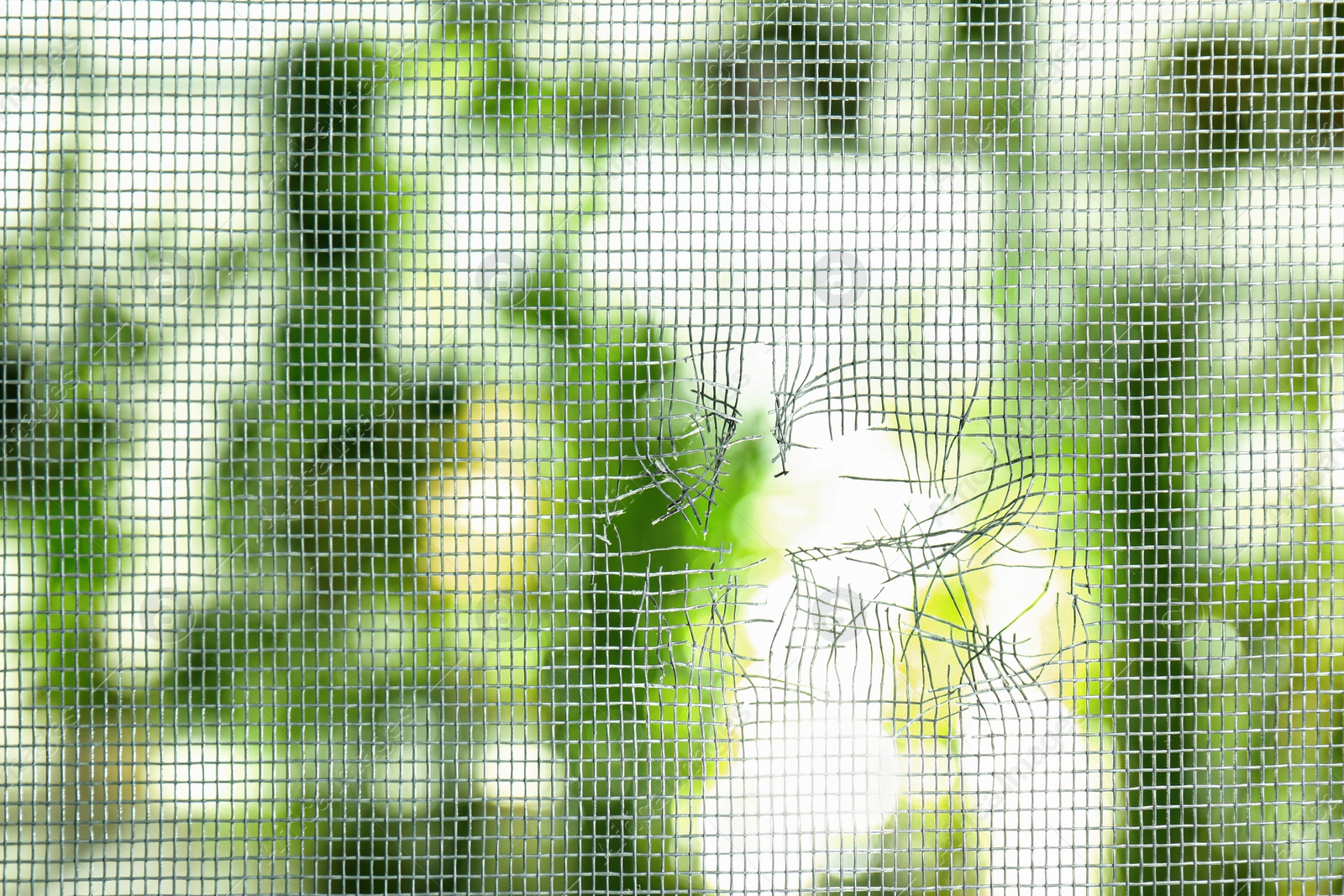 Torn window screen against blurred background, closeup Photo of Torn window screen against blurred background, closeup