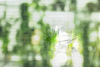 Torn window screen against blurred background, closeup Photo of Torn window screen against blurred background, closeup