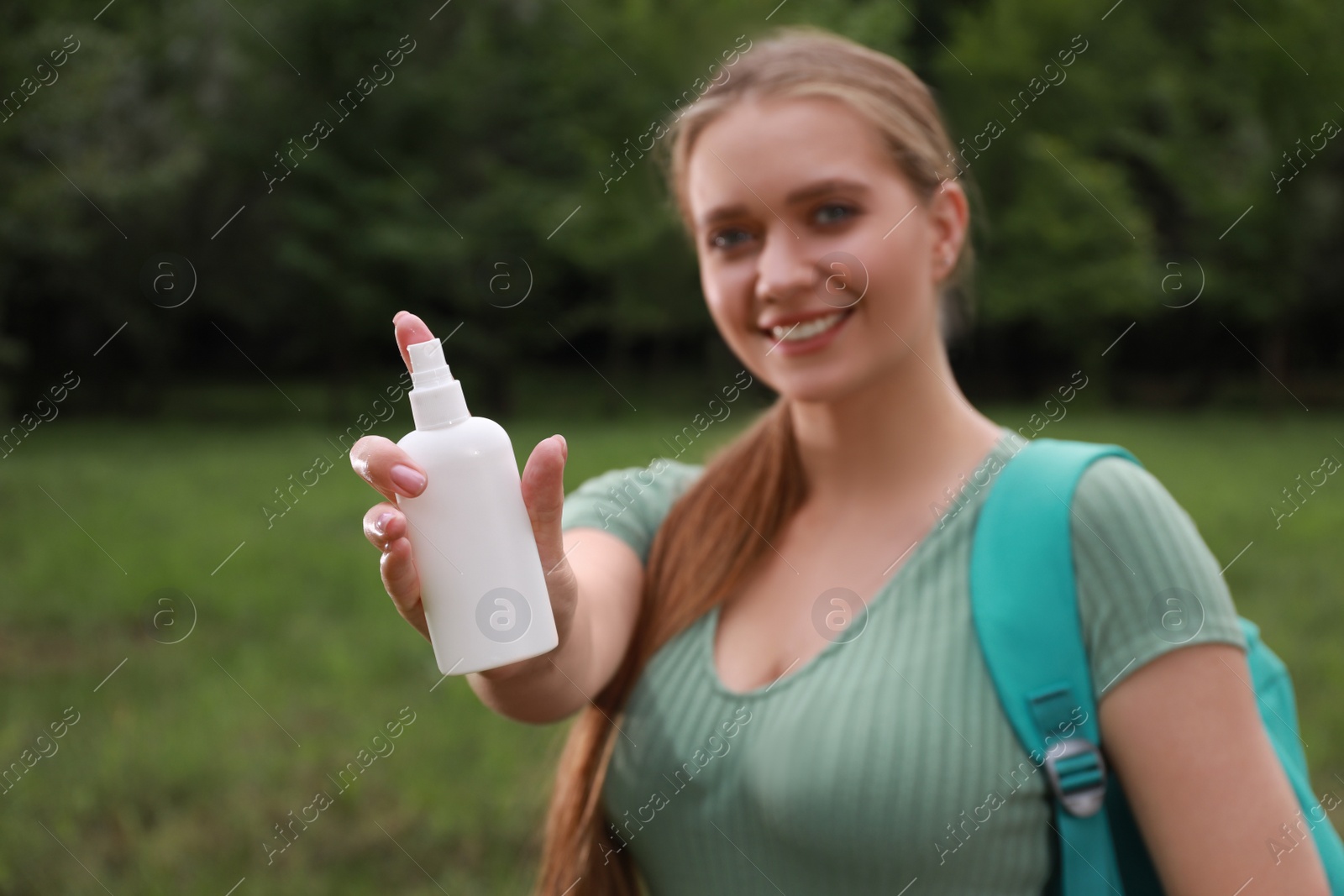 Woman with insect repellent spray in park, focus on bottle. Tick bites prevention Photo of Woman with insect repellent spray in park, focus on bottle. Tick bites prevention