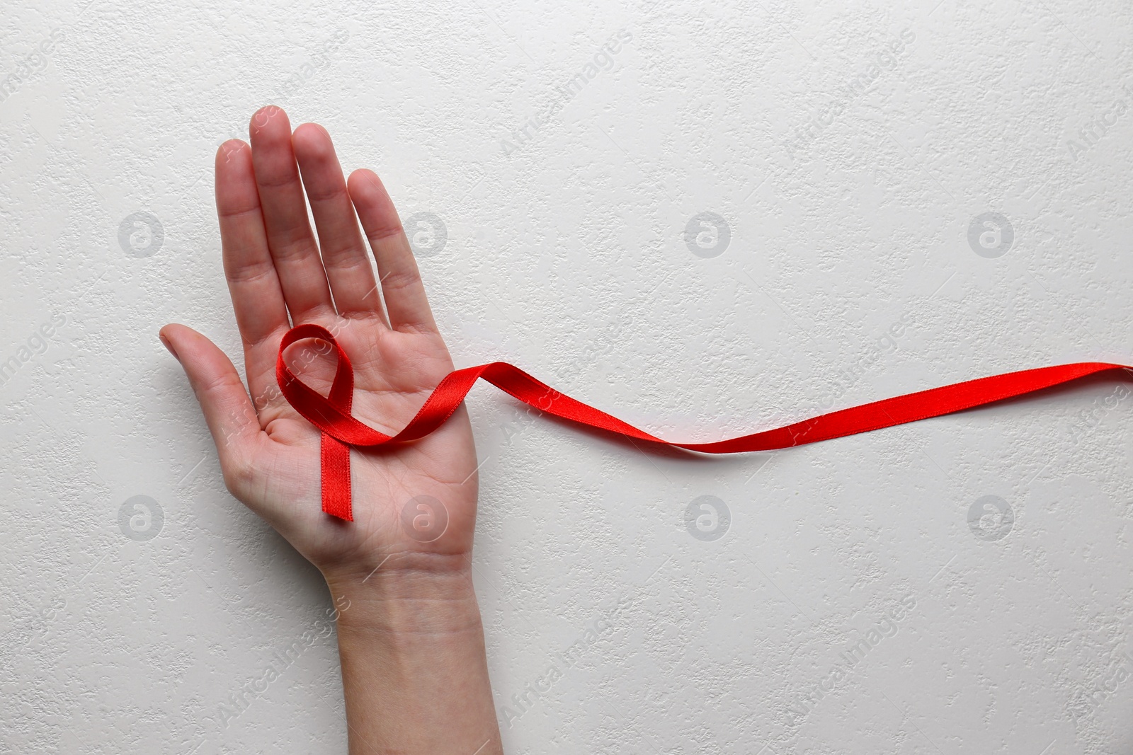 Woman holding red awareness ribbon on white background, top view with space for text. World AIDS disease day Photo of Woman holding red awareness ribbon on white background, top view with space for text. World AIDS disease day