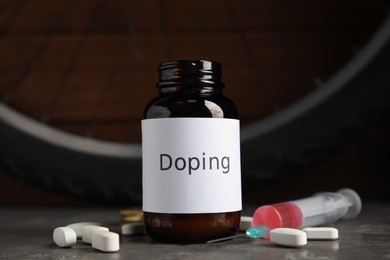 Pills, syringe and bike wheel on grey table. Using doping in cycling sport concept Photo of Pills, syringe and bike wheel on grey table. Using doping in cycling sport concept