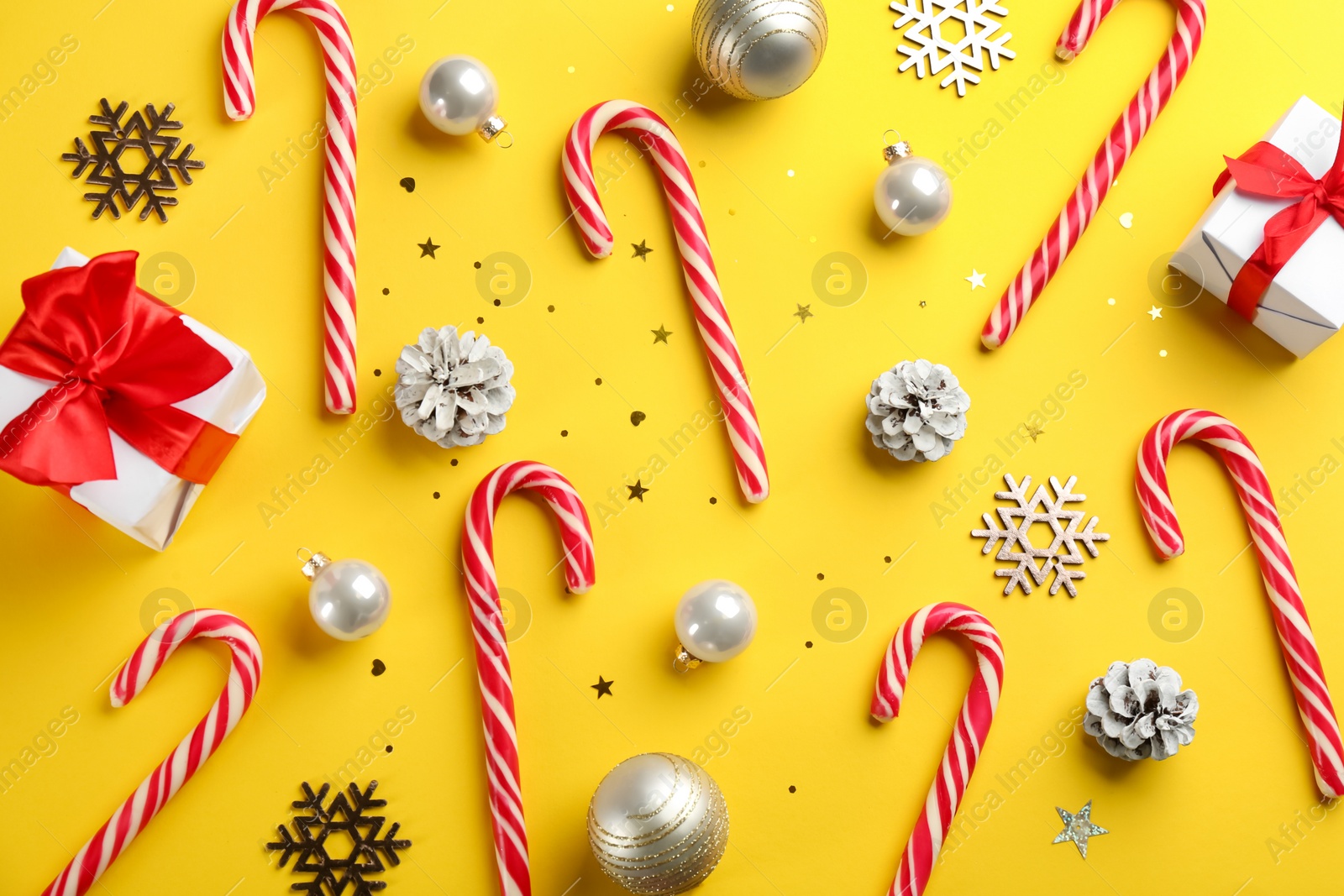 Flat lay composition with candy canes and Christmas decor on yellow background Photo of Flat lay composition with candy canes and Christmas decor on yellow background