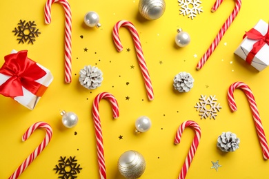 Flat lay composition with candy canes and Christmas decor on yellow background Photo of Flat lay composition with candy canes and Christmas decor on yellow background