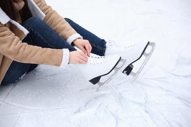 Woman lacing figure skate while sitting on ice, closeup Photo of Woman lacing figure skate while sitting on ice, closeup