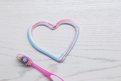 Heart made with toothpaste and brush on white wooden background, flat lay Photo of Heart made with toothpaste and brush on white wooden background, flat lay