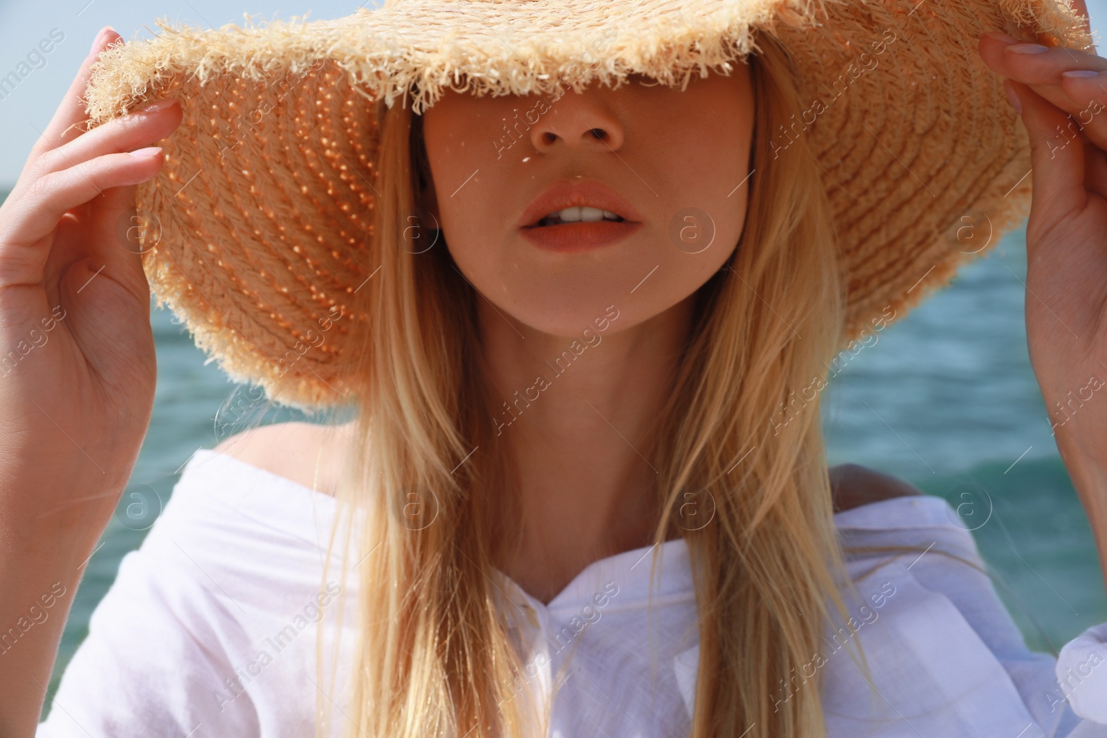 Young woman with straw hat near sea on sunny day in summer Photo of Young woman with straw hat near sea on sunny day in summer