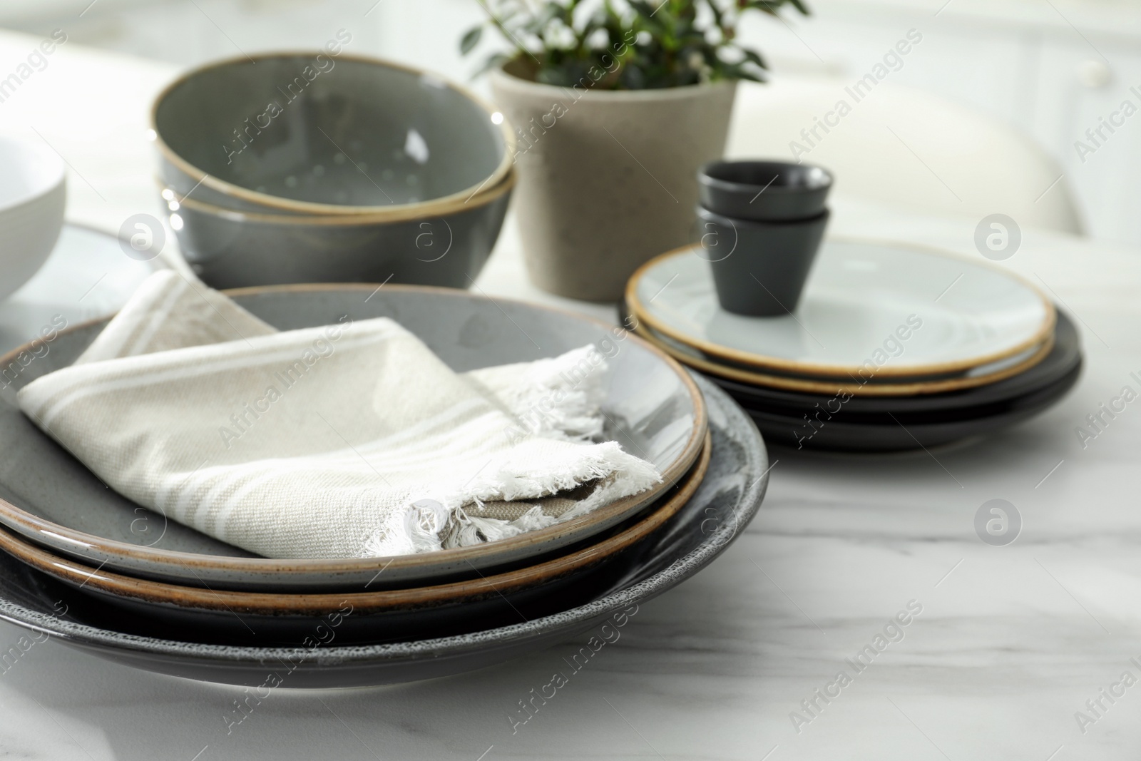 Set of beautiful ceramic tableware on white table in kitchen. Space for text Photo of Set of beautiful ceramic tableware on white table in kitchen. Space for text