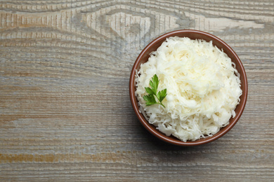 Photo of Tasty fermented cabbage with parsley on wooden table, top view. Space for text