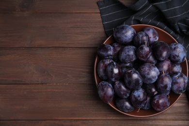 Delicious ripe plums in bowl on wooden table, top view. Space for text Photo of Delicious ripe plums in bowl on wooden table, top view. Space for text