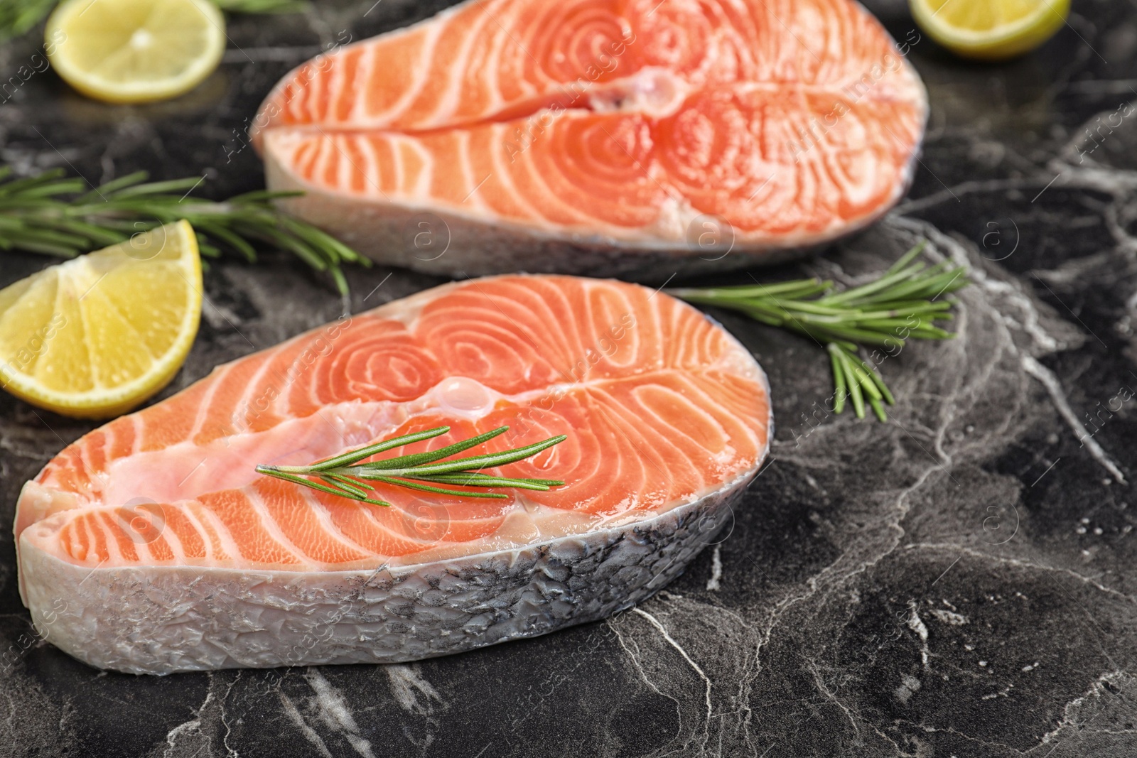 Fresh raw salmon, rosemary and lemon on black marble table. Fish delicacy Photo of Fresh raw salmon, rosemary and lemon on black marble table. Fish delicacy