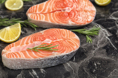 Fresh raw salmon, rosemary and lemon on black marble table. Fish delicacy Photo of Fresh raw salmon, rosemary and lemon on black marble table. Fish delicacy