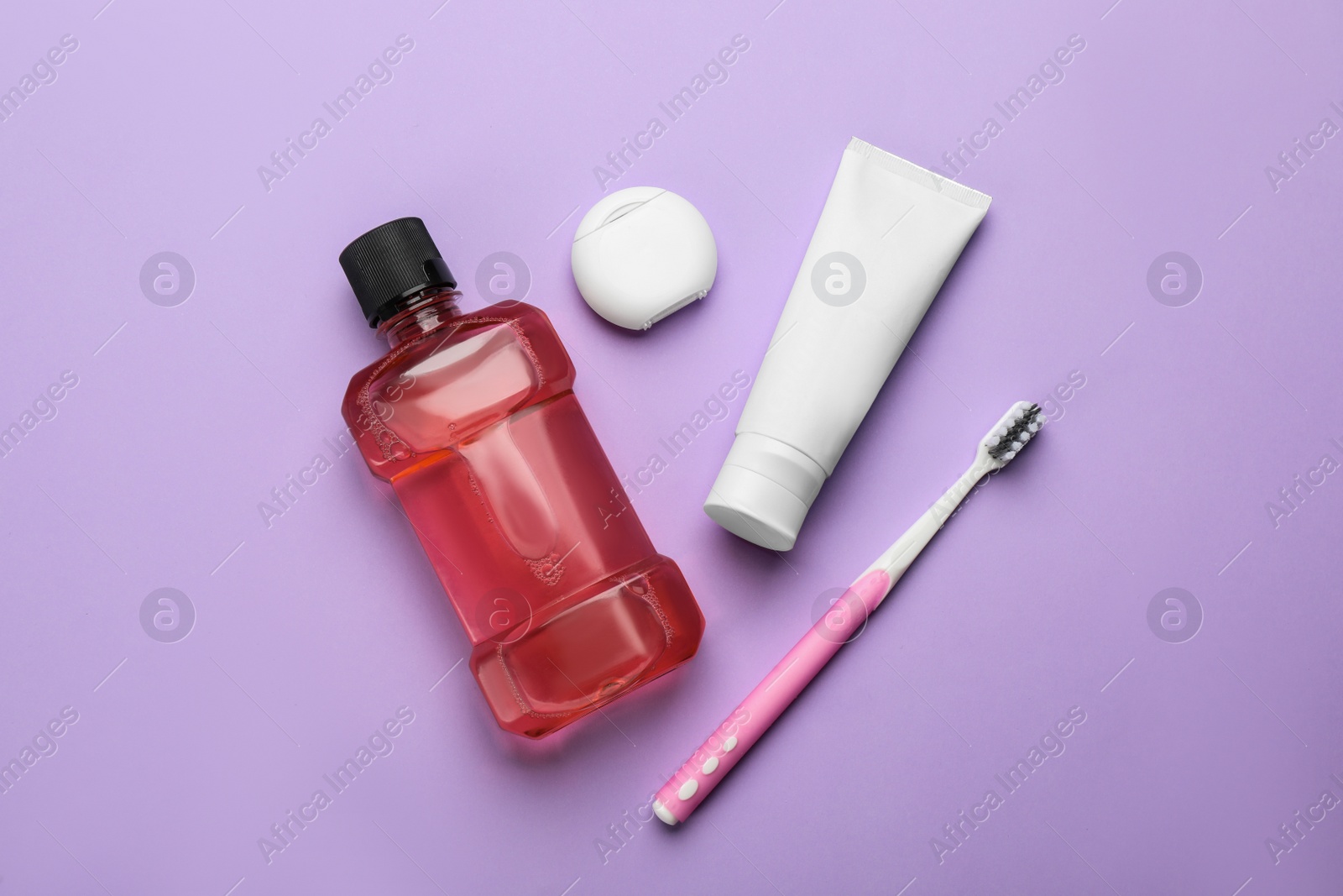Mouthwash, toothbrush, paste and dental floss on violet background, flat lay Photo of Mouthwash, toothbrush, paste and dental floss on violet background, flat lay