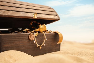 Open wooden chest with treasures on sandy beach, space for text Photo of Open wooden chest with treasures on sandy beach, space for text