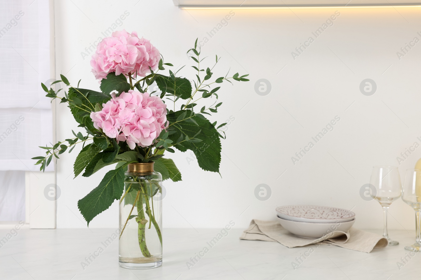 Beautiful pink hortensia flowers in vase on kitchen counter. Space for text Photo of Beautiful pink hortensia flowers in vase on kitchen counter. Space for text